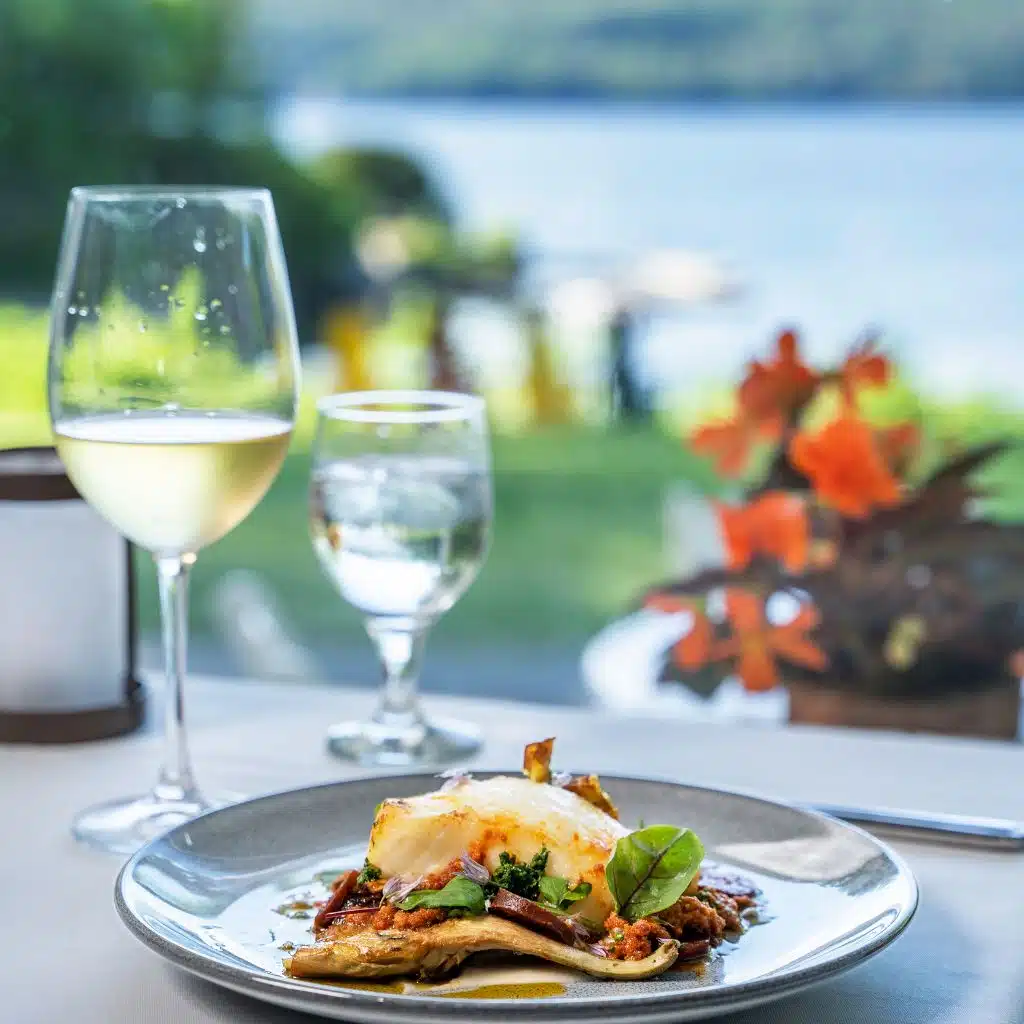 Entree and wine on table in Ardelia's restaurant with view of the harbor